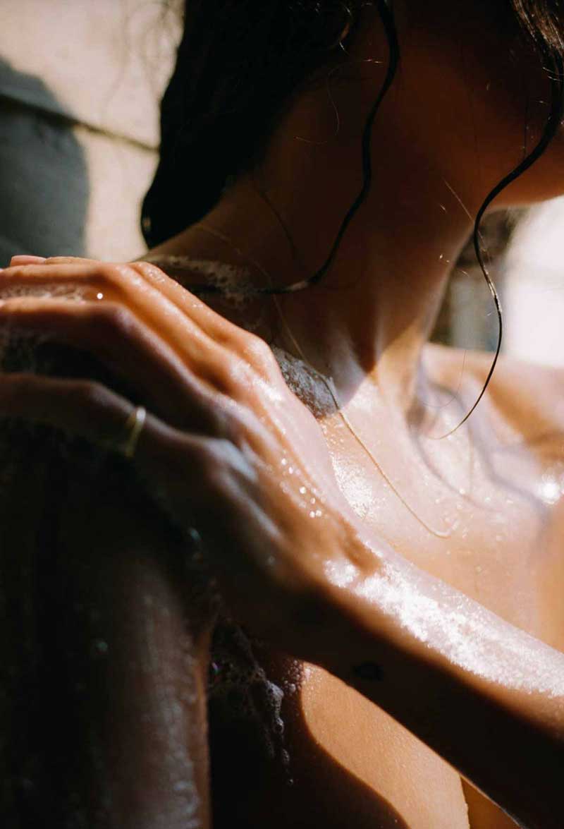 image of woman taking a shower with the acne trigger hairstyling product being shown