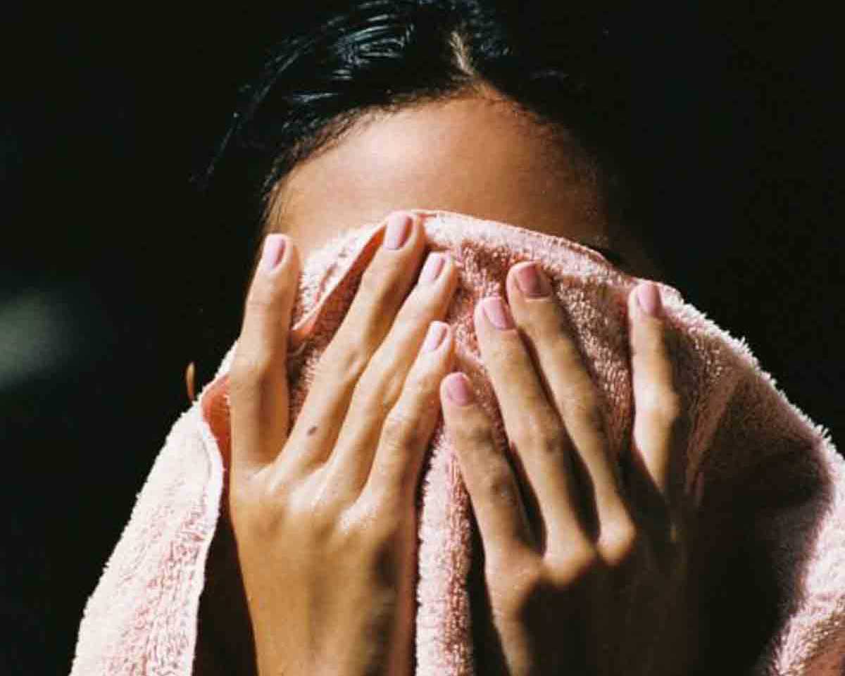 Cover image for the article The Best Skincare Routine for Rosacea-Prone Skin showing a woman drying her face