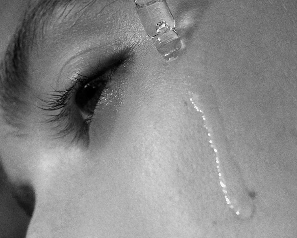 Black and white cover image for the article The Benefits of Facial Oils in Your Daily Skincare Routine showing a woman applying facial oil