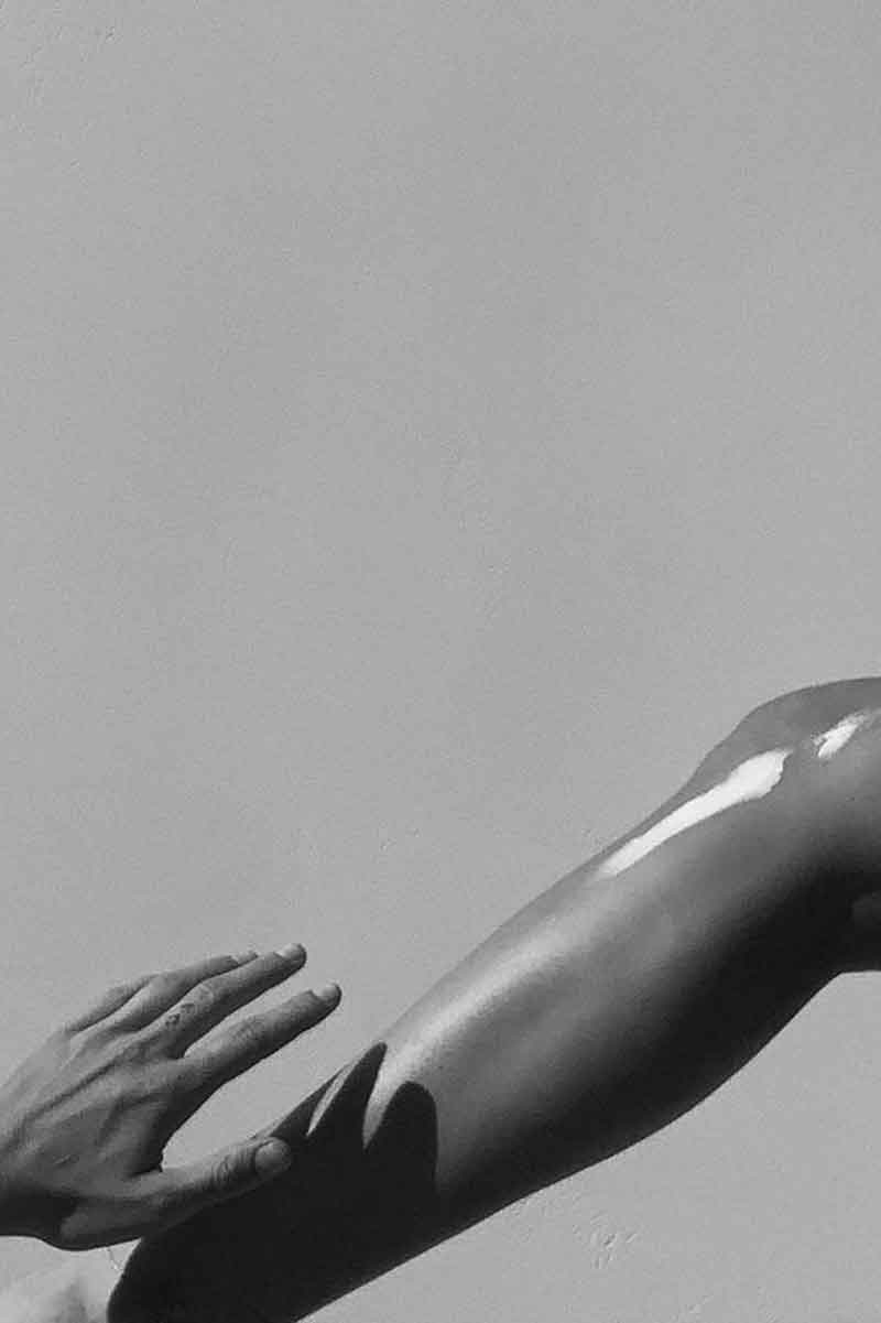 black and white picture showing a woman applying anti acne cream on her skin