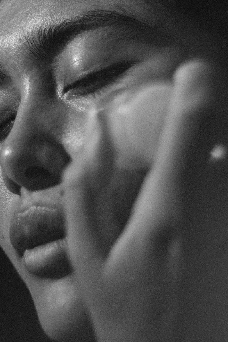 black and white picture of an asian beautiful woman taking care of her eyes skin concerns