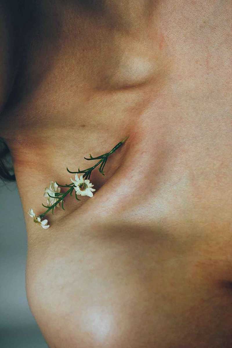 image of one of the natural ingredients to fight acne, chamomile, laying on a girl's neck