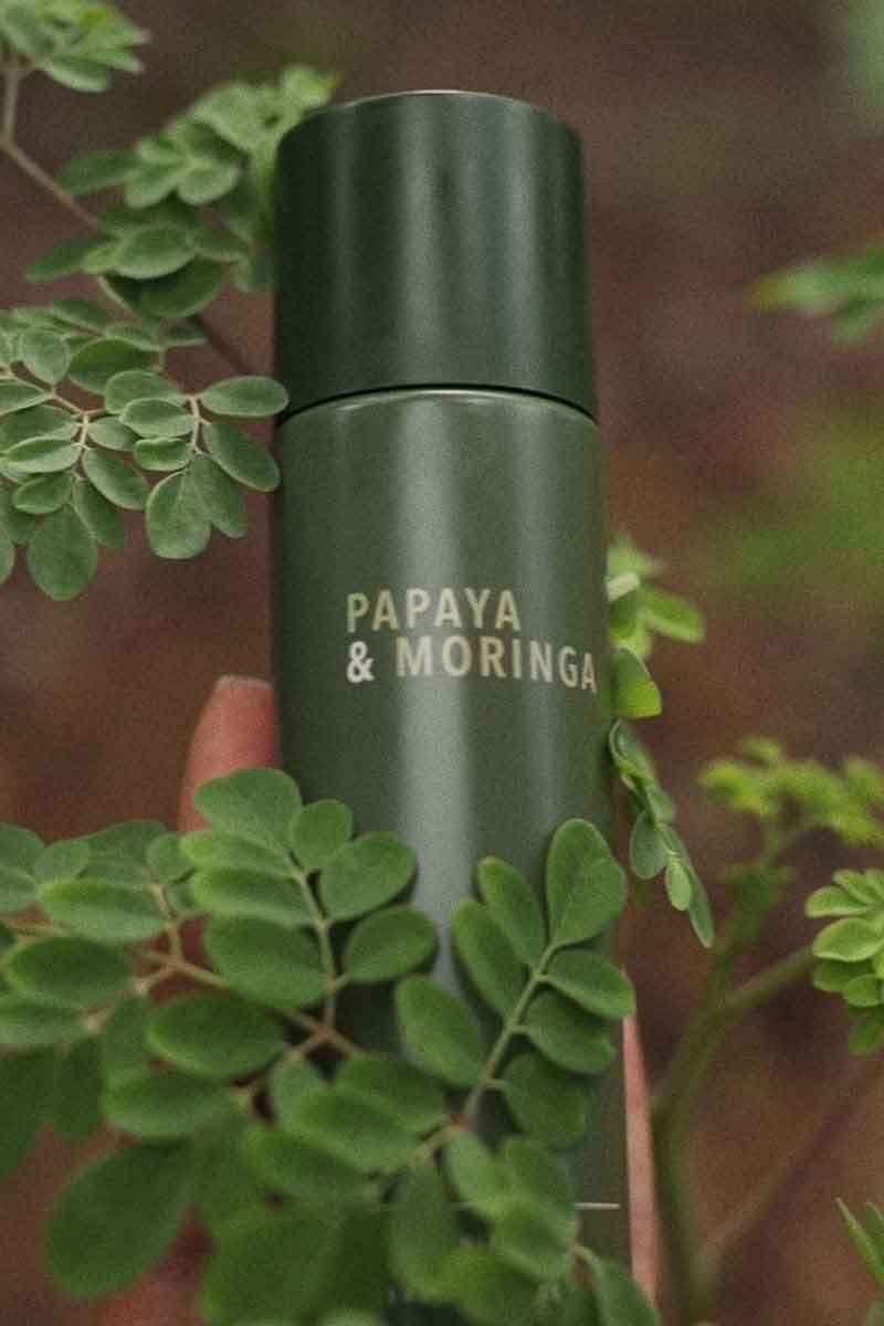 image of one of the sustainable skincare products by fields of yarrow being held amongst the leaves of a plant