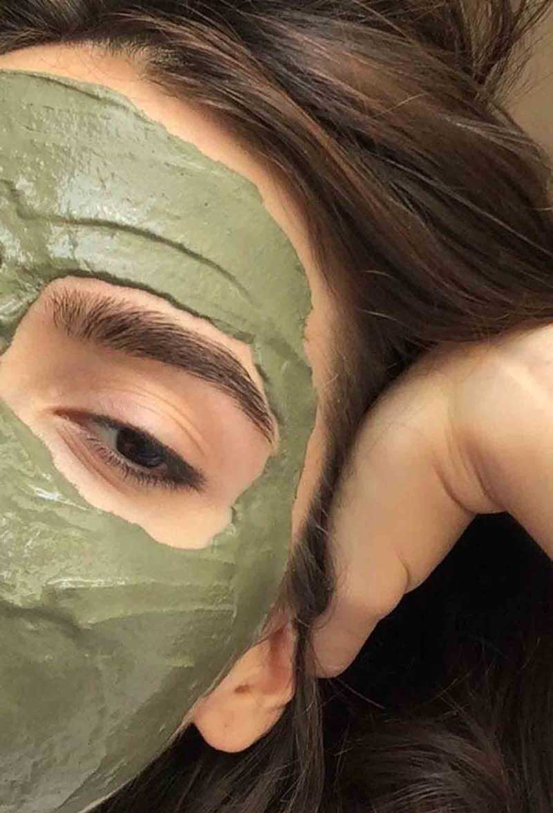 picture of a young woman using face masks as rosacea remedies
