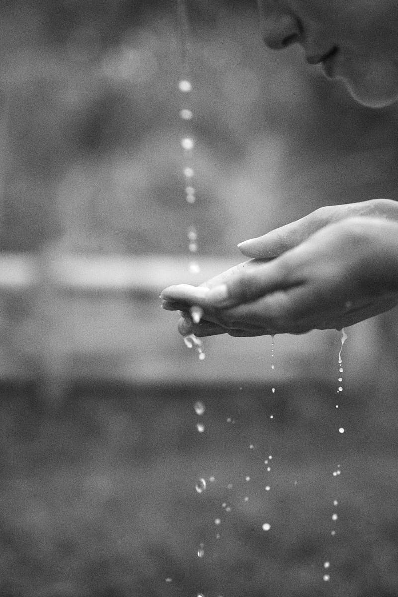 black and white picture of a woman's hand catching water to cleanse her face during a skincare routine