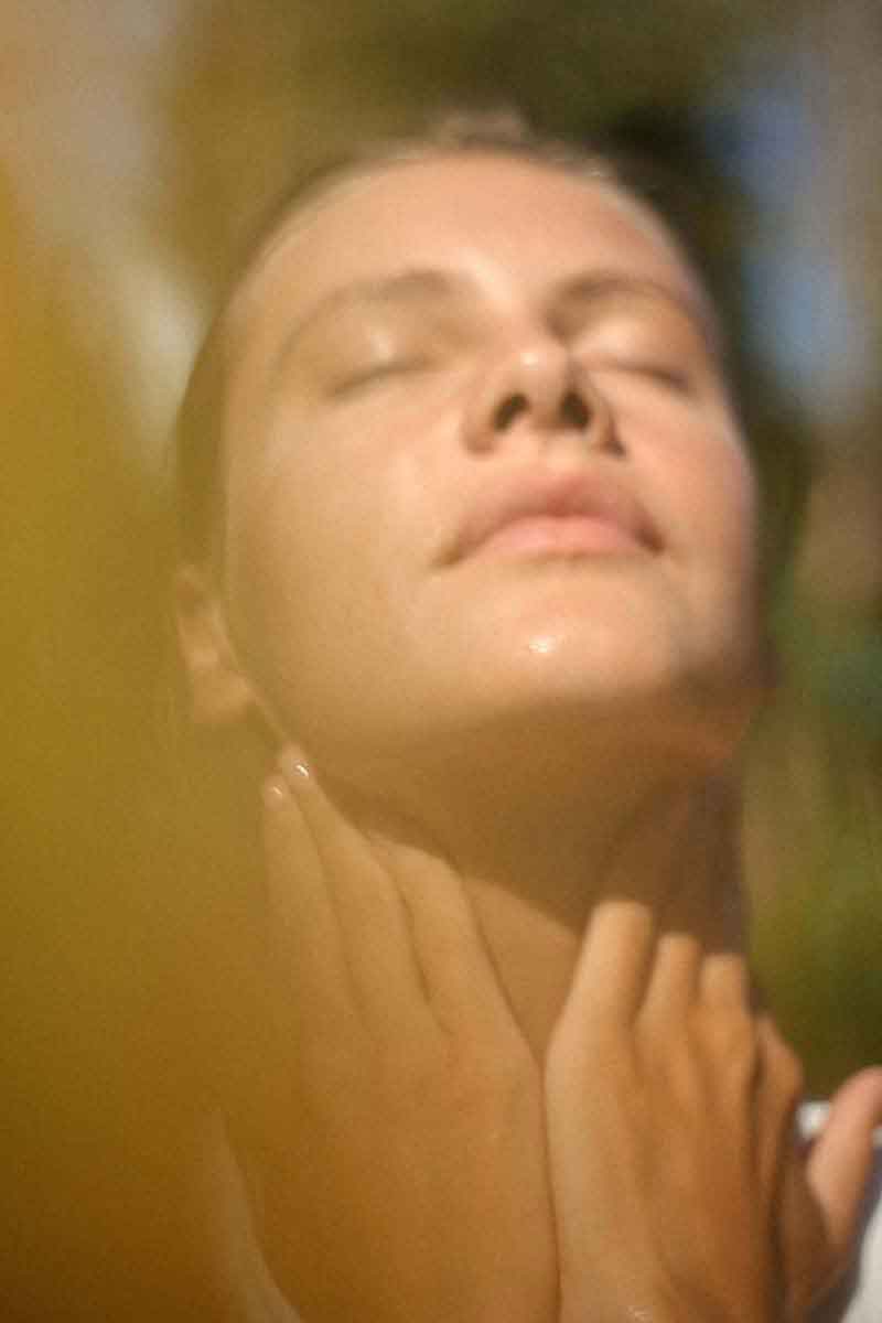 image of a woman in the nature applying her skincare routines with fields of yarrow products