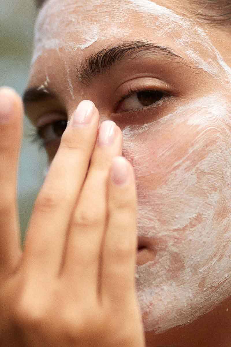 image of a woman applying a facial treatment with a fields of yarrow face mask