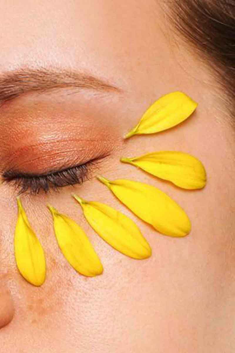 decorative picture of a model with flower petals underneath her eyes to reduce dark circles