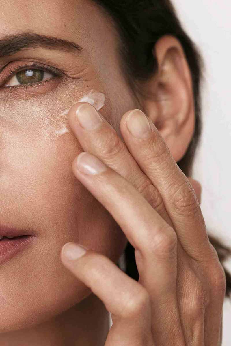 image of a mature woman using skincare products to reduce her fine lines