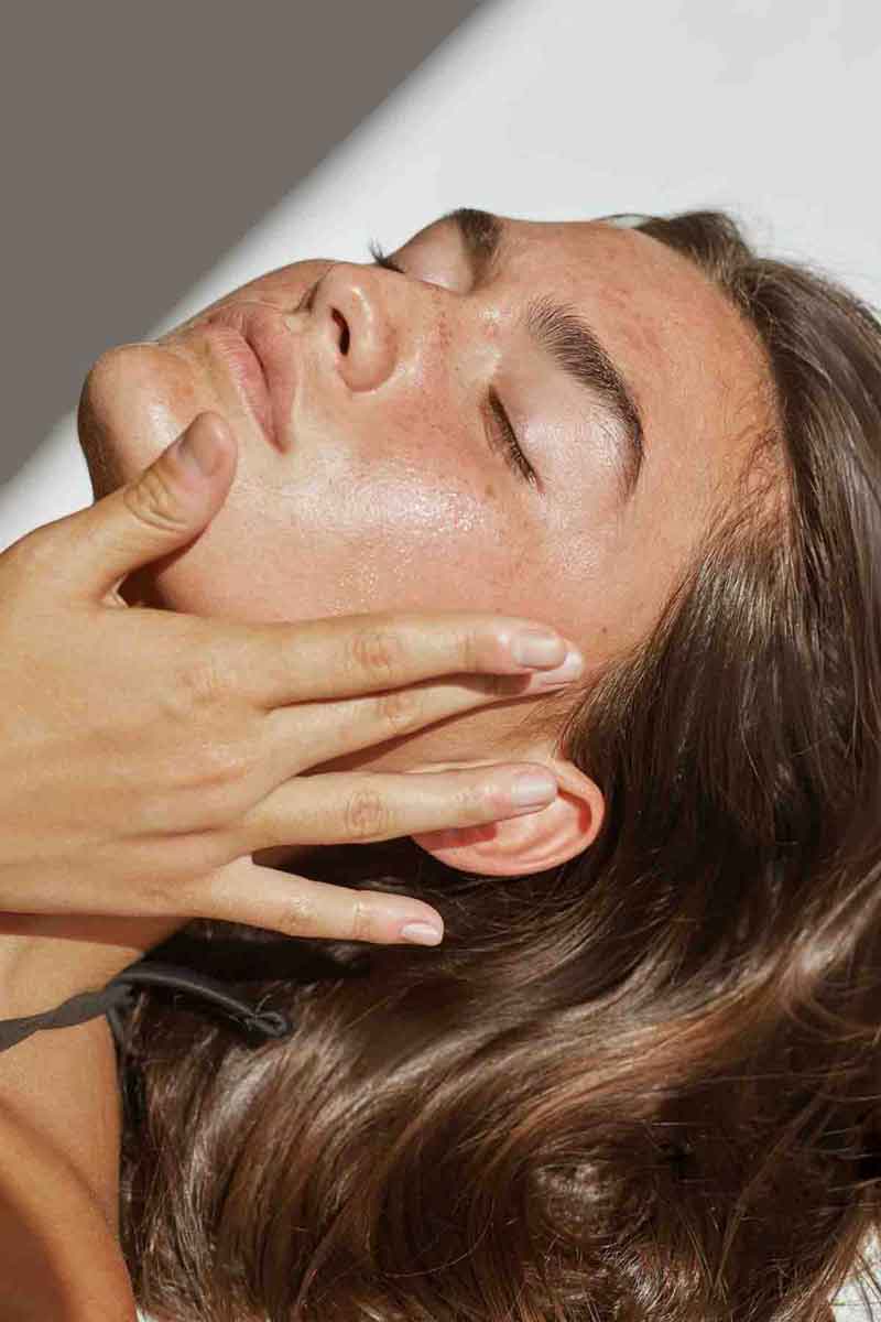 young woman applying moisturizer to her face