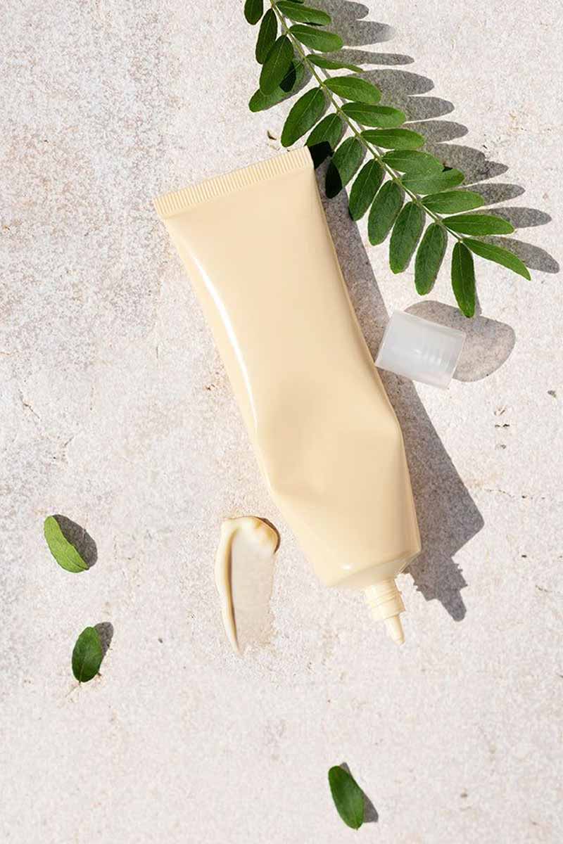 Picture of a skin cream with moringa leaves next to it